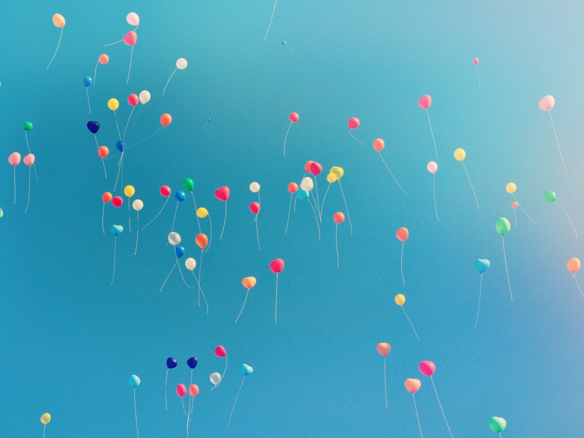 Balloons rising into an open sky