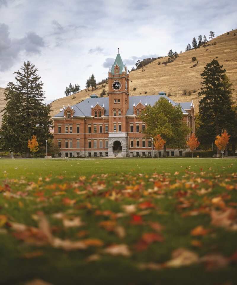 A university campus building across an autumn lawn
